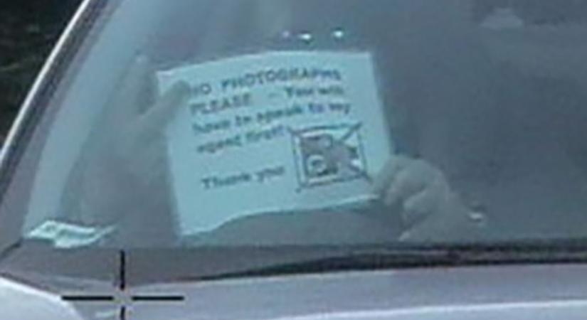 ” Ne fotózzon, kérem!” feliratú táblát mutatott fel egy rendőrségi kamerának